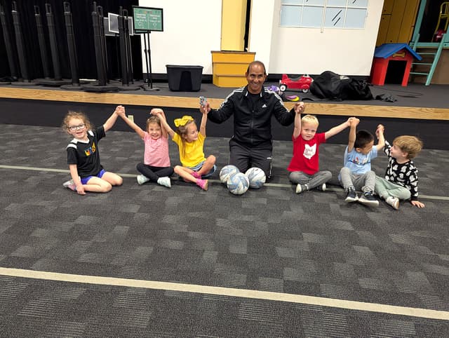 Coach Mo with young players at indoor training, everyone cheering