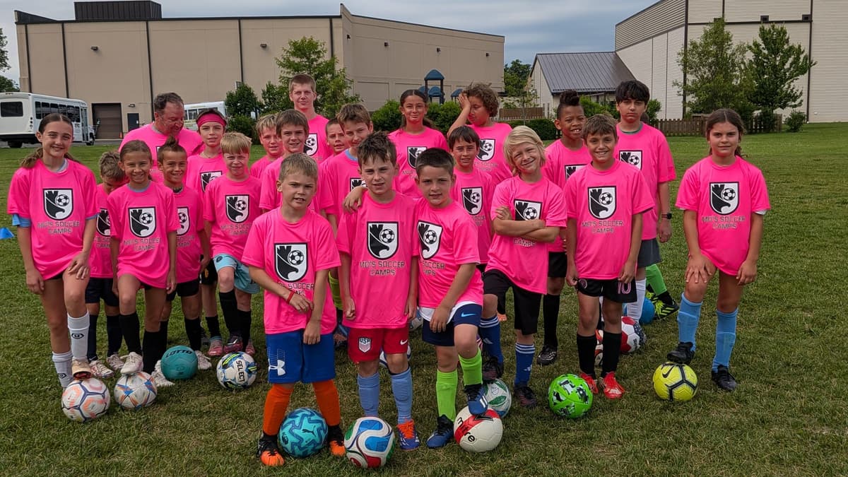 Campers in pink Mo's Soccer Camps shirts with Coach Mo, each with a foot on a ball, Summer Camp 2026